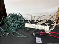 Overview of the lot showing two power bars, a green extension cord and a red heavy-duty extension cord.