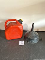 Gas can and funnel side view on a black surface with white background