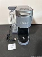 Frontal view of the Keurig coffee maker showing the brand logo, drip tray, and water reservoir.