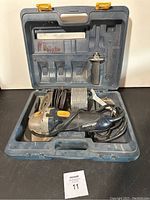Angle grinder and accessories organized inside a dark blue hard plastic carrying case, viewed from front with lid open.