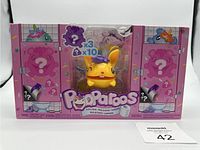 Photo showing front view of Pooparoos character figure in packaging with pink decorative box featuring toilet stall illustrations and branding.