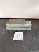 Three sharpening stones stacked on top of each other showing different sizes and surfaces.