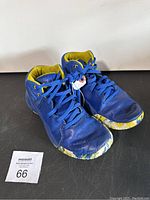 Pair of boys size 6Y Under Armour athletic shoes in blue and yellow with multicolored soles shown from a side angle against a white background.