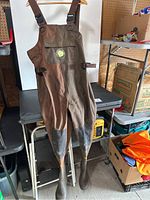 Full view of brown Northern Escape fishing waders hanging with attached boots, showing overall condition and design.