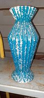 Front view of mid century art glass vase showing flared top and ribbed, spotted exterior design.