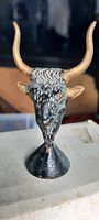 Front view of the black and gold painted bull head figure showing detailed texture and prominent horns.