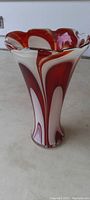 Photo of antique heavy art glass vase standing upright showing ruffled top and bold red and white swirled stripes.