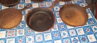 Top view showing six cast iron frying pans placed on a patterned tablecloth, all with visible surface rust.