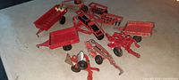 Photo showing entire collection of small metal toy farm implements including trailers, cultivators, seeders, and plows.