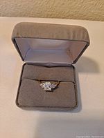 Gold tone ring with clear large faceted crystal shown in jewelry box interior