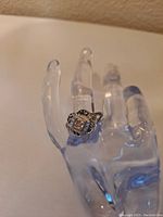 Close-up photo of the silver tone ring with clear crystal on a clear hand display.
