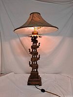 Full view of the stacked elephant table lamp with shade on and light glowing.