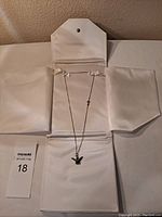Full view of sterling silver chain with firebird pendant inside a white jewelry display case.