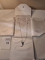 Sterling silver chain with scorpion pendant displayed on white jewelry display.
