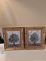 Two framed prints side by side showing trees with rustic wood frames and metal rivet details