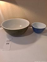 Two vintage Pyrex bowls - one green 4-quart and one blue 1.5-pint on tabletop.