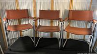 Three vintage mid-century tubular steel chairs side by side, showing overall condition and design.