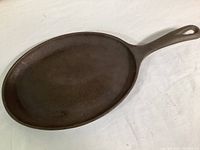 Top and side views of the oval cast iron skillet showing overall shape, depth, handle design, and surface condition.
