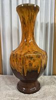 Full front view of tall porcelain vase showing the shape and glaze pattern in yellow and brown tones.