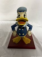 Front view of Donald Duck wooden nutcracker figurine in sailor outfit standing on red base.