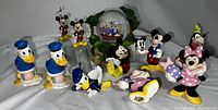 Full collection shown on white background with all figurines visible including Minnie, Mickey, Donald, Goofy and snow globe