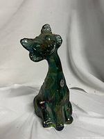 Front angled view of the winking alley cat sculpture showing the iridescent carnival glass colors and detailing.