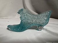 Side view of light aqua glass slipper showing pressed daisy and button pattern.