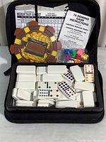 Display of Mexican Train domino set inside carrying case, showing domino tiles, train hub, colored train markers, scoring sheets, and instructions.