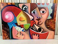 Full view of the cubist painting depicting two stylized faces kissing, a bird, and a watermelon slice in bright colors.