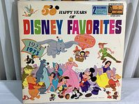 Front cover of 1973 Disney 50 Happy Years of Disney Favorites double album, showing colorful Disney character illustrations and album title.