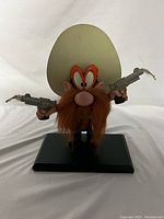Full front view of Yosemite Sam wooden nutcracker-style figure with large hat and guns standing on black base.