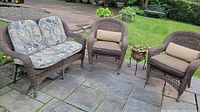 Photo showing full 3 piece outdoor rattan furniture set plus planter on a stone patio.