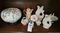 Full set of Asian inspired ceramics including lidded floral bowl, coffee pot, two fish vases, sugar bowl, and small floral cups and dishes on wooden shelf