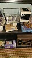 Clear Lucite organizer with handle, glass butter dish box, puzzle and other kitchen items on shelf.
