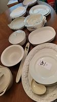 Tabletop view of various cream-colored Corningware dishes including casserole dishes with lids, pie dishes, and serving plates.