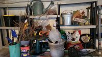 Front view of entire shelving unit packed with gardening supplies including watering cans, buckets, plant pots, soil bags, and garden decor.