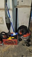 Photo showing Ridgid shop vacuum, handheld vacuum, mop, black vacuum wands, and crate with accessories