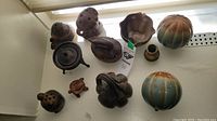 Top-down view showing all 11 small ceramic decor items arranged in a window corner. Items include turtles, an owl, a pumpkin, a vessel, and abstract shapes primarily in earth tone glazes.