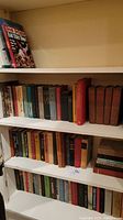 Multiple shelves of vintage books including hardcover and softcover editions, classic literature, and cookbooks.