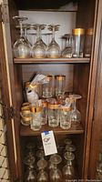 Shelf with multiple types of gold-rimmed stemware and glasses showing general assortment.