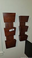 Two wooden wall-mounted holders with three compartments each, medium brown finish.