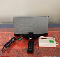 Bose SoundDock 3 system with remote and power adapter laid flat on a patterned surface.