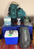 Full lot on display: two backpacks, cooler jug, lantern, heater, Coleman cooler, Intex bag