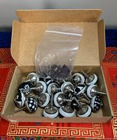 Box of 20 hand painted ceramic cabinet pulls showing metal screw bases and attached ceramic tops with various black and white patterns. Plastic bag with screws included.
