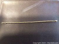 10k gold rope chain bracelet laid flat on black textured surface showing full length and rope pattern