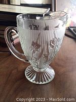 Clear EAPG glass pitcher featuring raised iris flowers and herringbone pattern on the body, with flared ridged base and comfortable handle.