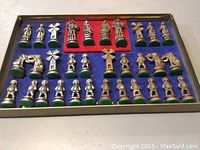 Full view of silver-tone chess pieces arranged in box with blue and red felt lining.