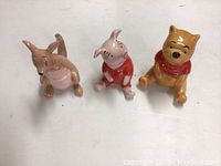 Front view of three ceramic Disney figurines: Kanga, Piglet, Winnie the Pooh, all sitting