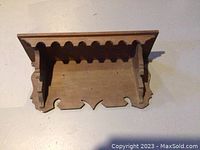 Top and angled view of the ash wood wall shelf showing scalloped edge and bracket sides with decorative cutouts.