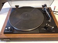 Front view of Denon SL-5a turntable showing wooden base, platter with rubber mat, tonearm and control knobs